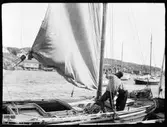 En man hissar segel på en båt. Troligen Fiskebäckskil, Bohuslän.