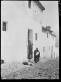 Kvinnor i porten till ett vitrappat stenhus. Troligen Ronda, Spanien.