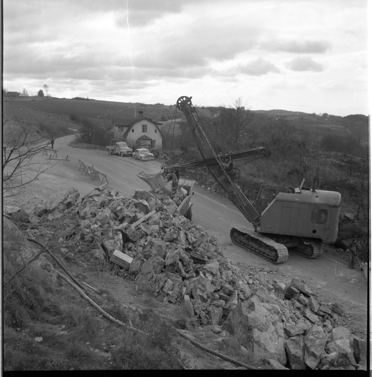 Percy Heldebrandt, Excavator in work at Galgen in connection with the motorway construction at Gränna/Röttle, stage II. At the house stands a police car - Volvo Amazon.