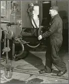 Personvagnsreparatör Einar Larsson, vid Trafikaktiebolaget Grängesberg–Oxelösunds Järnvägars järnvägsverkstad i Eskilstuna, demonstrerar hur olyckan som höll på att kosta honom tårna gick till.  Skyddsskon räddade hans tår i samband med arbetsplatsolyckan då en 150 kilos buffert föll ner på hans fot.