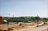 Vy från Folkets hus mot ost, okänt årtal. Till vänster skymtas Svalövsbolaget (röd byggnad). Mark schaktas mellan Göteborgsvägen och Mölndals järnvägsstation för nybyggnad av motorvägen E6/E20. Huset i bildens mitt byggdes under 1930-talet och kallades för 