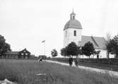 Gällaryds kyrka i Värnamo kommun. Kyrkan byggdes mellan åren 1782-1786 under ledning av murarmästare Hans Lundström, Laholm. På vägen framför kyrkan står kommunister (senare kyrkoherde) G Ek i halmhatt och kantor Alfred Hultqvist.