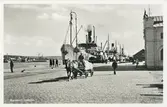Fraktfartyg vid stora hamnkajen. Tullpackhuset skymtar i högra kanten. Åkare med hästdragen kärra. Vykort.
