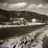 Vy över Lövagård i Veddige med landsvägen i förgrunden. Ett lätt snötäcke har fallit.