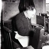 Kloar-Erik sitter och fixar med en gammal kamera.