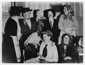 Gruppbild med 8 kvinnor, stående och sittande, från Alingsås Kooperativa Kvinnogille, klädda som påskgummor och påskgubbar under en påskfest.