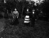 Gruppbild på två kvinnor och en man i en trädgård.