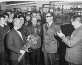 Förste kontrollör Bertil Lindberg (t,v,) uppvaktar med blommor från postkontoret och dess personal. T.h. applåderar sparkonsulent Valter Strömberg, från Postspar-banken