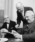 Förre byrådirektören, i Postbanken, Carl Wilhelmsson skriver i gästboken, övervakad av byrådirektör Karl Axel Lundin. T.v. förre postbankschefen, sedermera riksgäldsdirektör Fredrik Sandberg.