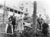 4 män och en kvinna arbetar, på en sluttning, runt ett träd. Bakom dom syns Bolltorps sanatorium med tillhörande veranda.