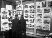 Två japaner studerar ett antal svart/vita fotografier med svenska motiv.
Statens Järnvägar deltog i denna utställning i Japan.