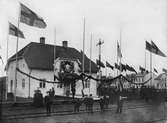 Invigning av Enköping - Heby - Runhällens Järnväg vid Enköpings hamn station, 1906. Notera att flaggorna ser inverterade ut, detta är en bieffekt av den typ av film, ortokromatisk film, som användes vid den här tiden.