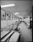 Elektrisk modelljärnväg, under uppbyggnad, föreställande Stockholm södra - Älvsjö. I bakgrunden jobbar konstnären G. Palmgren med bakgrunden till modellbanan.