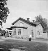 Örbyhus stationshus från gatusidan. Tvåaxlig rälsbuss. Trafikplatsen öppnades 1874. På 1950-talet byggdes ny stationsbyggnad som syns på bilden. Ett tvåvåningshus i trä.