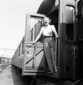 Statens Järnvägar, SJ tåghem under uppehåll på okänd plats. Kvinna vid öppen dörr på sovvagn. Vagn SJ A04 2071.