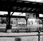 Affischer på Hallsberg station. På Helsingforsaffischen syns de olympiska ringarna. Helsingfors tilldelades de olympiska spelen 1947, vilka sedermera hölls 1952. Bilden troligtvis tagen i slutet av 40-talet eller början av 50-talet.

Affischer:
SJ Familjebiljett
Storstroemsbroen
Holland
Stockholm - med Sveriges statsbanor
Besök Helsingfors - Nordens vita stad
Cóte Basque
Malborough Sounds New Zealand

Skylt: SJ Skyddsrum
