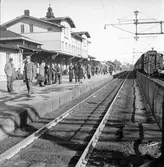 Resenärer vid Skövde station. Till höger på bilden ett persontåg.