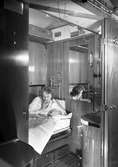 AB02c, 1:a klass sovvagn. Kvinnan läser tidning och röker en cigarett.