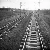 Dubbelspår med 2 typer av betongslipers. Järnvägsövergång och en lutningsskylt