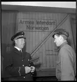 Samtal mellan stationsinspektor och banarbetare framför en tysk godsvagn.