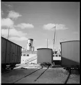 Postfartyg och godsvagnar vid en hamn.