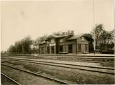 Station anlagd 1866-67. Stationshuset, tvåvånings i trä, tillbyggdes i båda ändar 1899 och i dessa tillbyggnader rymdes expedition samt 2 klass väntsal. Bangården har utbyggts i tre etapper, senast i samband med elektrifieringen 1949. . HLJ passerade UWHJs spår i plan på bangården 
HLJ , Lidköping - Håkantorps Järnväg
UWHJ , Uddevalla - Vänersborg - Herrljunga Järnväg