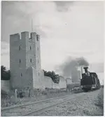 Tåg vid Visby ringmur. Ånglok GJ lok 5 ”Roma”. Loket tillverkades 1894 vid Nydqvist & Holm AB, Trollhättan. Det blev skrotad 1952. Under perioden 1948-1952  ägdes av Statens Järnvägar som SJ K3p 3076.