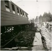 Vy på urspårad vagn och folksamling efter tågolycka.