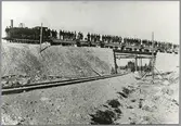 Bergslagernas Järnvägar, BJ U 5, med banarbetare ståendes på grusvagnarna. På linjen mellan Grängesberg - Hörken. Spåret under tillhör Frövi - Ludvika Järnväg, FLJ.