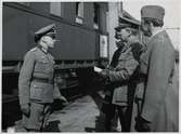Två svenska militära befäl och en svensk polis samtalar med ett tyskt befäl i samband med att ett tyskt sjukvårdståg passerar Hallsberg under Andra Världskriget.