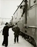 Emil Klerhult, platsföreståndare vid stationen i Vrena, lämnar vagnslista och föraruppgift om antal axlar och tågvikt till lokförare Evert Ahlin på tåg 8045 sedan medarbetaren vid stationen, Uno Larsson, rapporterat att växlingen är klar. Trafikaktiebolaget Grängesberg - Oxelösunds Järnvägar, TGOJ Bt 307.
