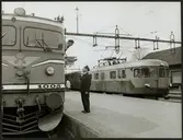 Statens Järnvägar, SJ Rb 1005 och Trafikaktiebolaget Grängesberg - Oxelösunds Järnvägar, TGOJ motorvagnståg, lokförare i samtal vid stationen i Flen maj 1964.