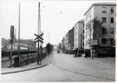 Järnvägsgatan i Sundbyberg. Till vänster ligger järnvägsövergången längs Stationsgatan. I bakgrunden skymtas Sieverts Kabelverk. På sträckan mellan Sundbyberg och Huvudsta C.