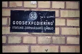 Skylt på tegelfasad med texten: SJ GODSEXPEDIERING STATENS JÄRNVÄGARS OMBUD.