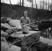 Flickan Ann-Sofie sitter på en sten vid ån nedanför Filianen i Veddige där man fiskade.