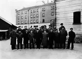 Gruppbild på anställda vid Alingsås Bryggeri. Främre raden från vänster: Karl Axel Andersson, Edvin Larsson, Kamrer Herr Forslund, Ägare och disponent Sten Möller, Kontorist Einar Stångberg, Gustav Larsson, Arthur Kronberg, Bengt Fahlström. Bortre raden från vänster: Nils Gustavsson, Herr Nyman, Synerska Britta Samuelsson, Sigfrid Linusson, Chaufför Åke Hansson, Gunnar Ekstrand, Arvid Andersson, Synerska Fru Annie Larsson, Nils Granberg. Grupp utanför bryggeriet.