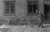 Fritz Johanssons Maskinaffär på Kungsgatan 28 (Nygrens fastighet) i kvarteret Pärlan, Alingsås. Rolf Andersson står här på gården och justerar bakhjulet på en cykel.