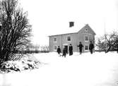 Tvåvånings bostadshus, 5 personer i snön framför huset.
August Perssons bostad.
Karl Persson