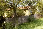 Ett gult bostadshus i putsad fasad bakom ett staket på Trollbackevägen. Ägaren hette Skillius och byggmästaren Bertil Danielsson.
