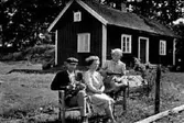 FAMILJEN KARL SCHÖNBORG SITTANDE FRAMFÖR BOSTADSHUSET.                                       
MANNEN HAR TRE RÄVUNGAR I KNÄT.