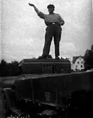 EN MAN STÅR PÅ TAKET PÅ EN LASTBIL. I BAKGRUNDEN SYNS 
SJÖMANSKYRKAN.