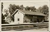 Spårsida av Sandhem stationshus med hus i bakgrunden.