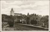 Spårsida av station med vy på bangård och Strömstad kyrka.