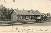 Gods på tralla med personal vid stationshus.