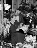 Kvinna och man i bostadsmiljö omgiven av blommor, läser telegram, Östhammar, Uppland,