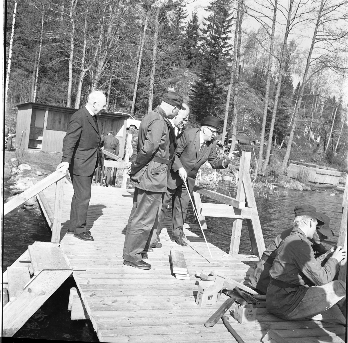 Percy Heldebrandt, Men on a bathing bridge at the Blind Home in Bunn. In the foreground, some younger men are sitting in military attire on the dock among carpenter tools.