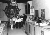 En barnkör som sjunger under ledning av organist Eva Karlsson i Kållereds kyrka, Svenska kyrkan, innan 1976.