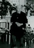 Hulda Hansson (1876 - 1975) sitter omgiven av blommor, här på ett sjukhem. Hon arbetade som hushållerska hos konsul Kindal på Vasagatan i Göteborg. Kindal ägde Gumperts bokhandel. Efter pensioneringen bosatte hon sig i sitt föräldrahem Vommedal Västergård 