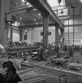 Arboga Mekaniska Verkstad, Meken, interiör. Några män, iklädda overaller, arbetar med maskiner i en stor fabrikslokal. Det hänger traverser i taket.

25 september 1856 fick AB Arboga Mekaniska Verkstad rättigheter att anlägga järngjuteri och mekanisk verkstad. Verksamheten startade 1858. Meken var först i landet med att installera en elektrisk motor för drift av verktygsmaskiner vid en taktransmission (1887).  Gjuteriet lades ner 1967. Den mekaniska verkstaden lades ner på 1980-talet.
Läs om Meken i Hembygdsföreningen Arboga Minnes årsbok från 1982.