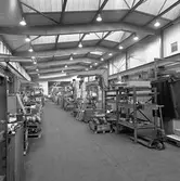 Arboga Mekaniska Verkstad, Meken, interiör. 
Fabrikslokal med maskiner och hyllor med maskindelar.
25 september 1856 fick AB Arboga Mekaniska Verkstad rättigheter att anlägga järngjuteri och mekanisk verkstad. Verksamheten startade 1858. Meken var först i landet med att installera en elektrisk motor för drift av verktygsmaskiner vid en taktransmission (1887).  Gjuteriet lades ner 1967. Den mekaniska verkstaden lades ner på 1980-talet.
Läs om Meken i Hembygdsföreningen Arboga Minnes årsbok från 1982.